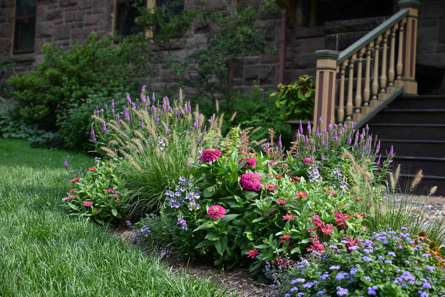 A decorative garden with various flowers and plants near a building