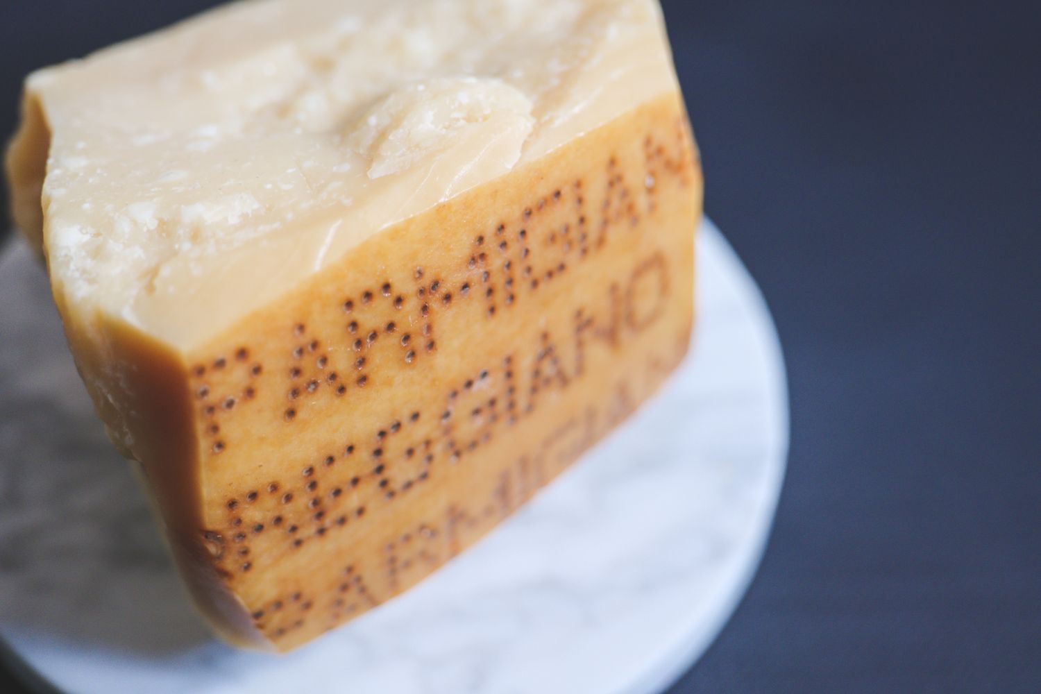 A piece of ParmigianoReggiano cheese on a marble surface