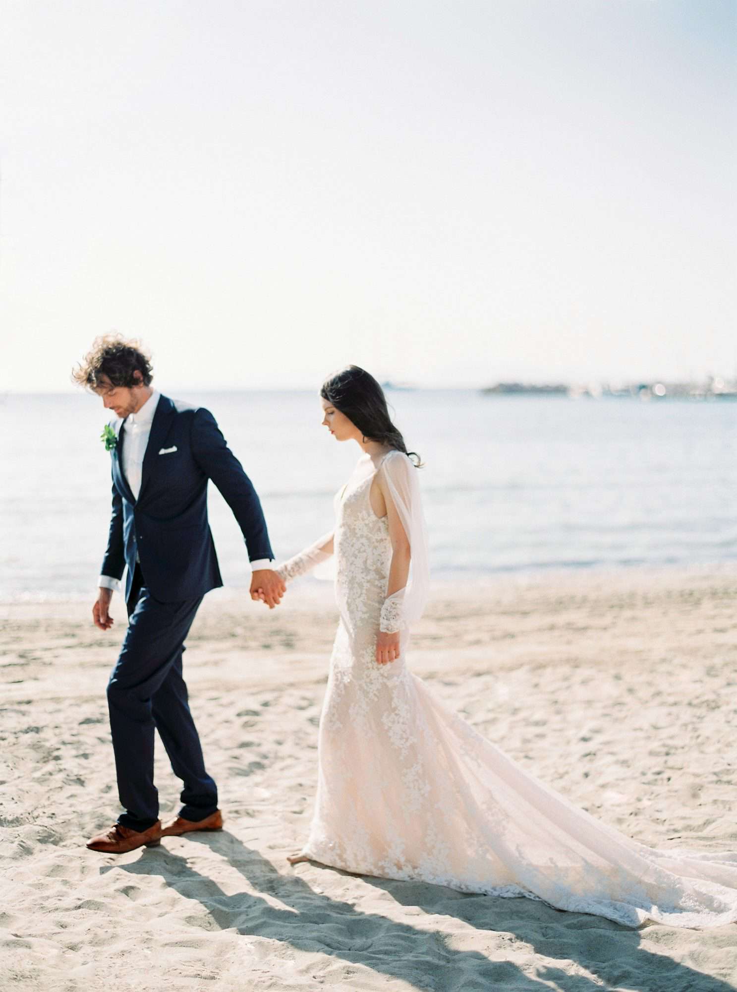 beach wedding dresses bride and groom holding hands on waters edge
