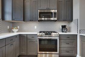 Modern kitchen with dark cabinets stainless steel appliances and patterned tile backsplash