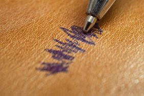 A pen leaving a stain on a leather surface