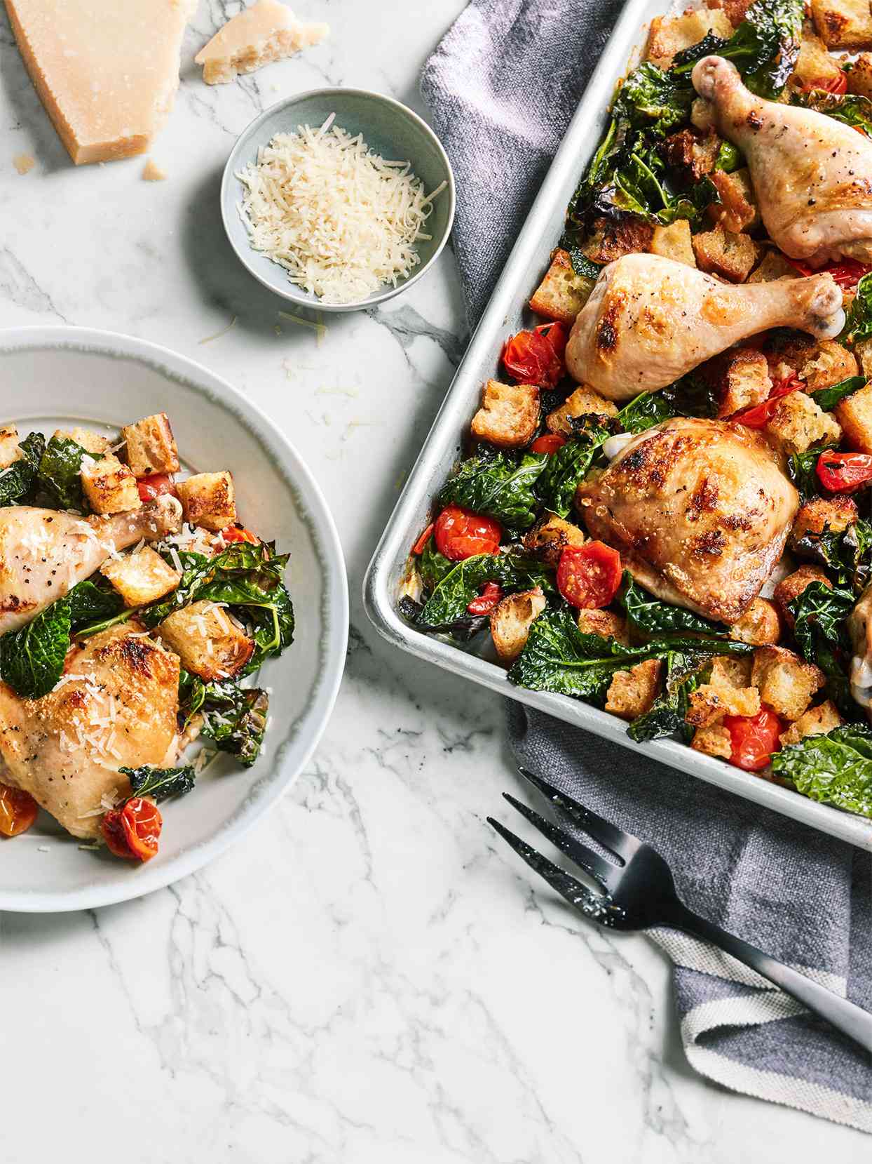 plate and sheet of chicken and kale dinner on marble table top