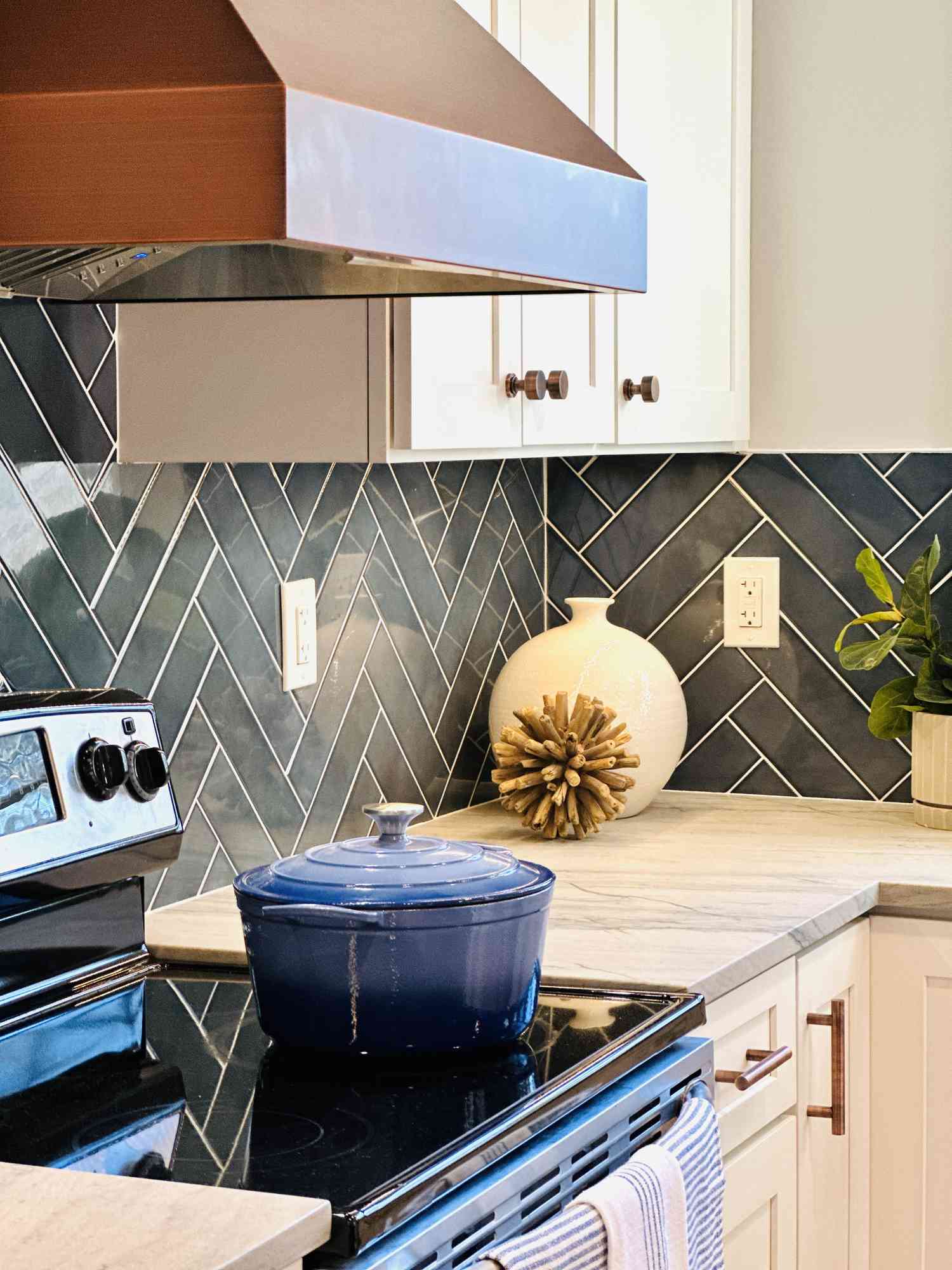 blue tile with white kitchen cabinets and brass hardware