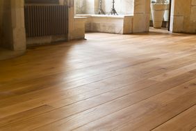 Smooth wooden flooring in a room with stone walls and a radiator