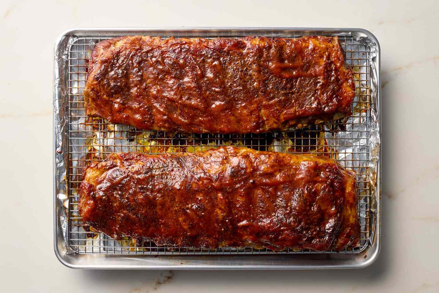 Two racks of ribs roasted on a wire rack placed on a baking sheet