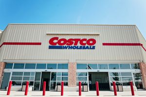 Front of a Costco Wholesale store with red bollards and a blue sky overhead