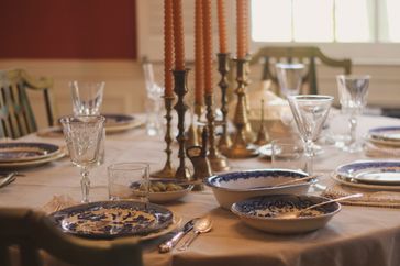 A dining table set with plates glasses utensils and candles