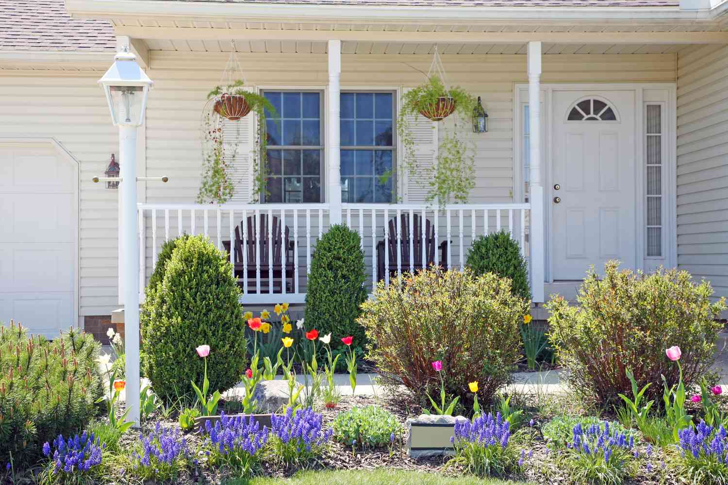 Pretty vinyl clad ranch home with Amish made chairs on the porch, and lovely Spring landscaped yard.