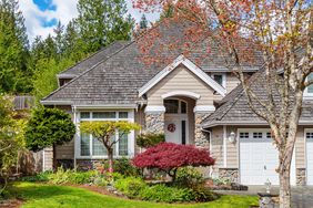 Beige home with front yard with trees and flowers