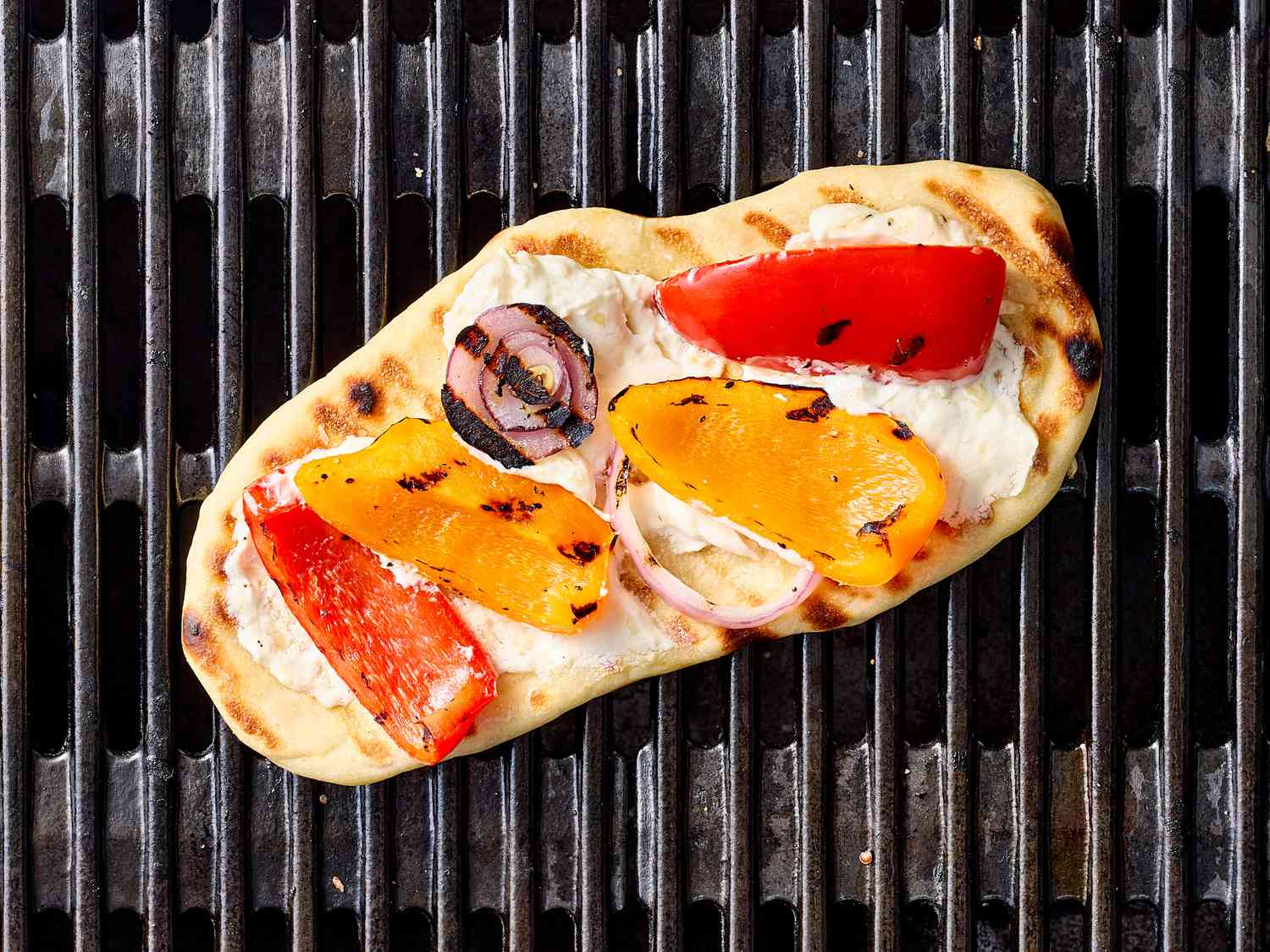 Grilled flatbread topped with vegetable slices on a griddle