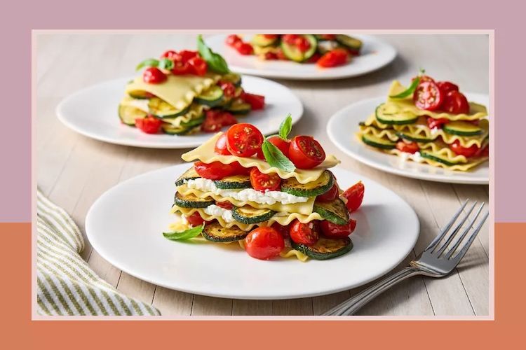 Plated layered vegetable lasagna garnished with tomatoes and basil