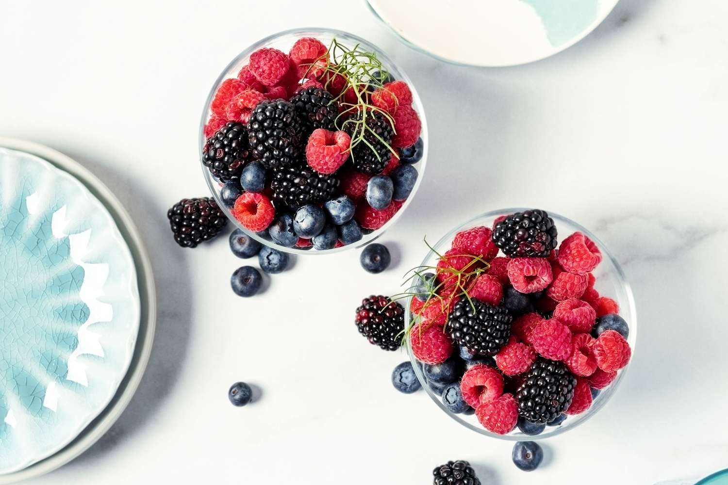 Two bowls of mixed berries including raspberries blackberries and blueberries