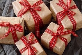 Gift boxes wrapped in brown paper with red plaid ribbons arranged on a dark surface