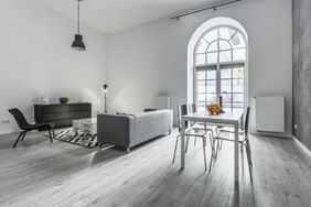Modern living space with a sofa dining table and large arched window
