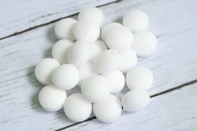 Stack of white round mothballs on a wooden surface