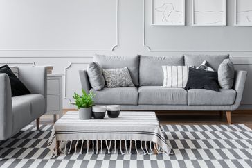 A modern living room with a sofa striped rug and a coffee table