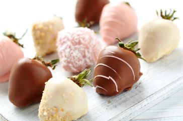 Strawberries covered in chocolate on a white wooden table