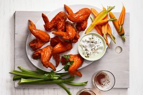 A plate of buffalo wings with a side of blue cheese dip celery sticks and carrots