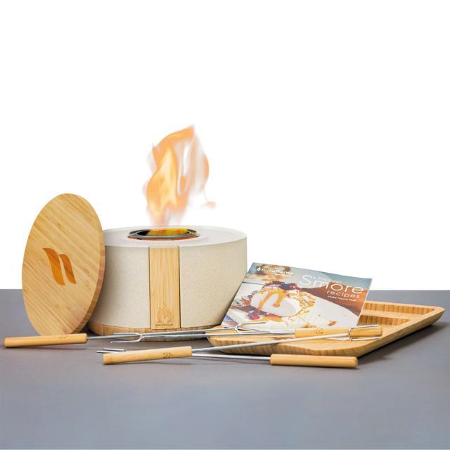 A tabletop fire pit with accessories including skewers and a tray designed for making smores