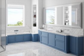A modern bathroom with blue cabinets large mirrors and a bathtub under a window
