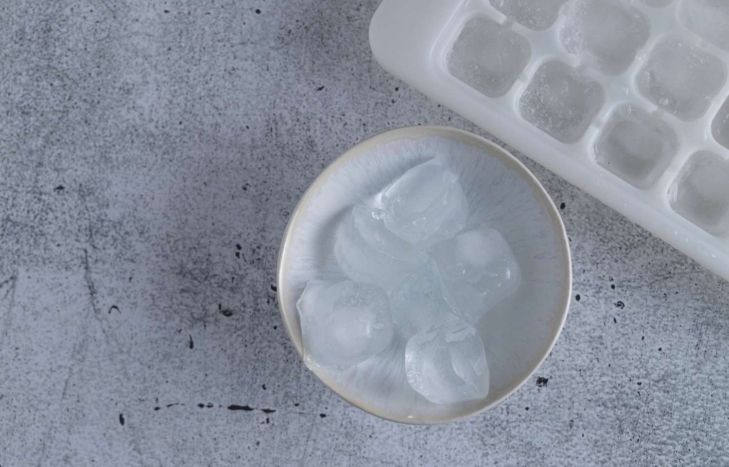 bowl of ice cubes next to an ice cube tray