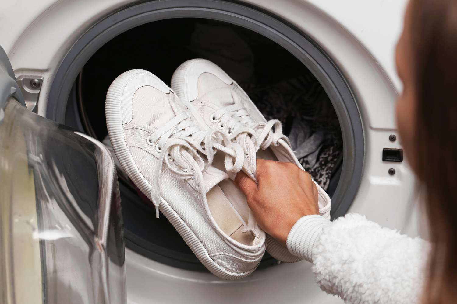Person placing sneakers into a washing machine