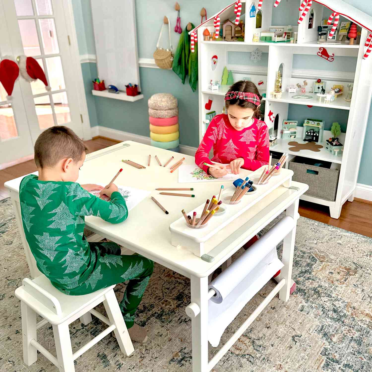 two kids crafting at a white table in their festive pajamas