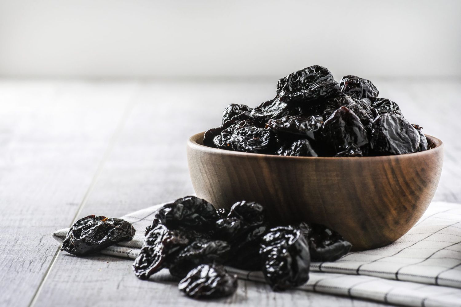 dried prunes in wood bowl