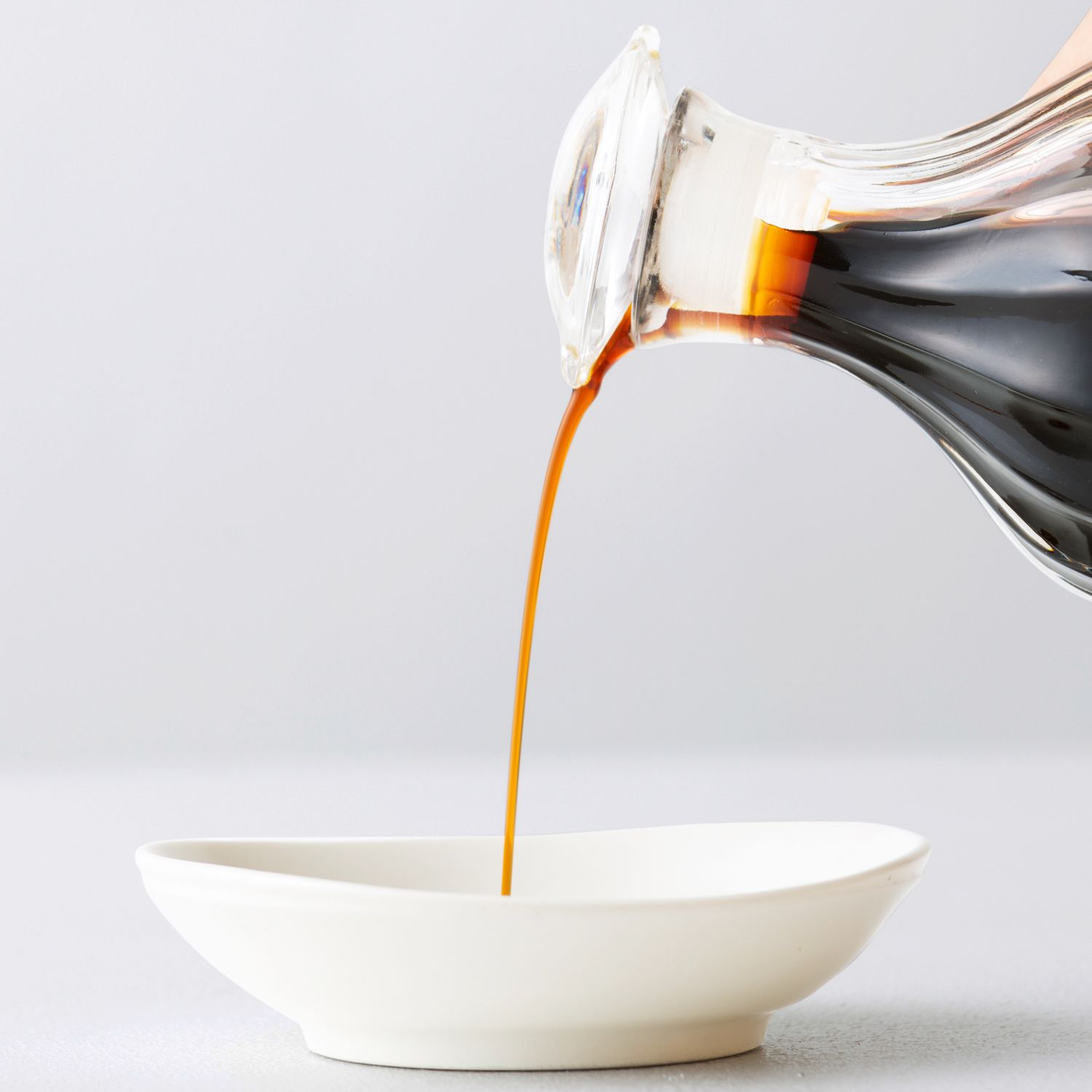 soy sauce being poured into a white dish