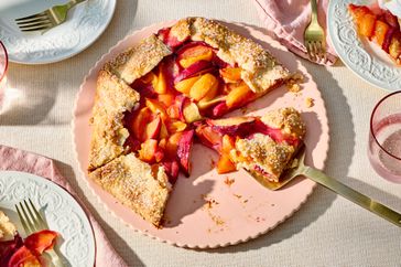Stone fruit galette partially sliced, placed on a decorative plate with forks on the side