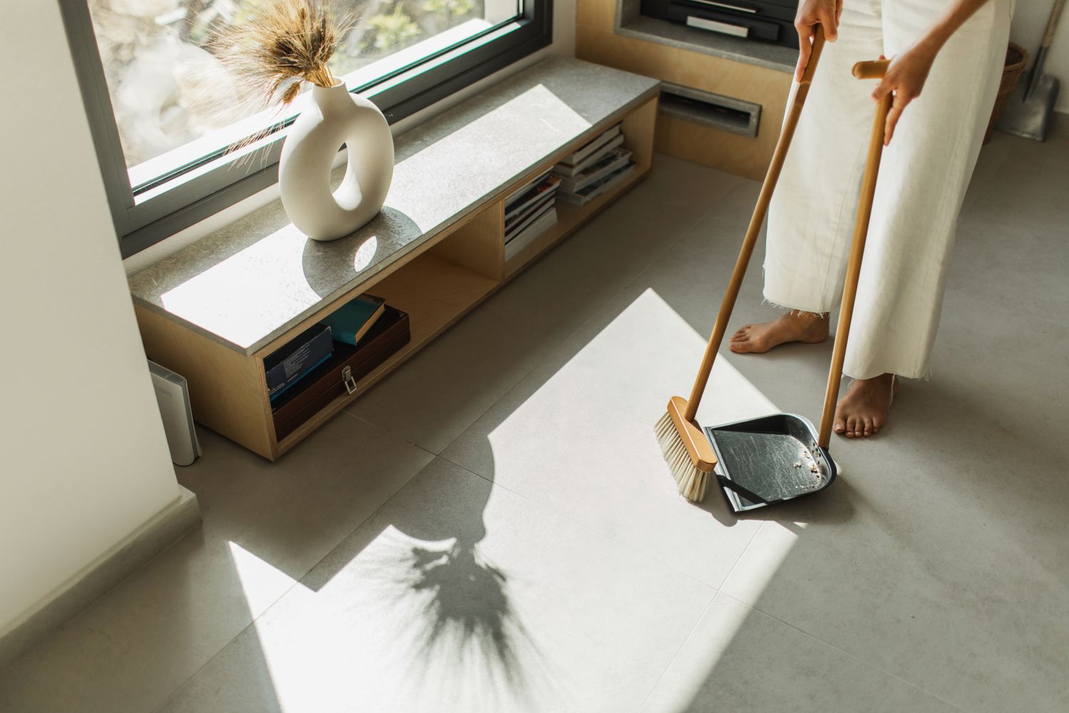 Person sweeping a modern room with a broom and dustpan