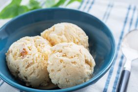 Three scoops of ice cream in a blue bowl on a fabric with a striped pattern