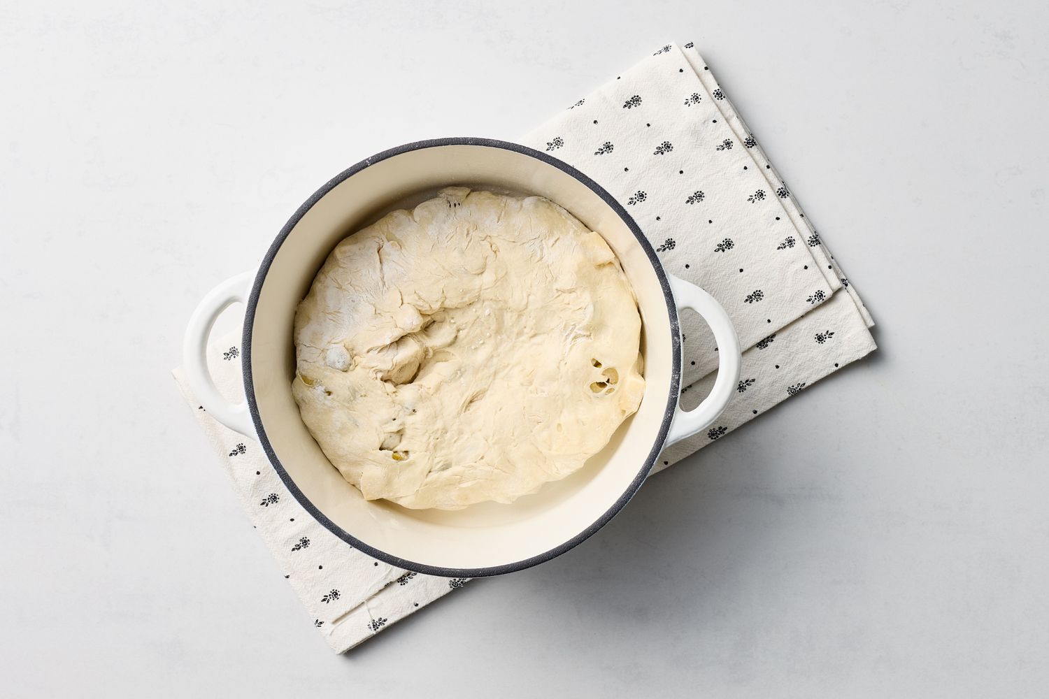 Baking dough prepared in a round pan over a patterned cloth