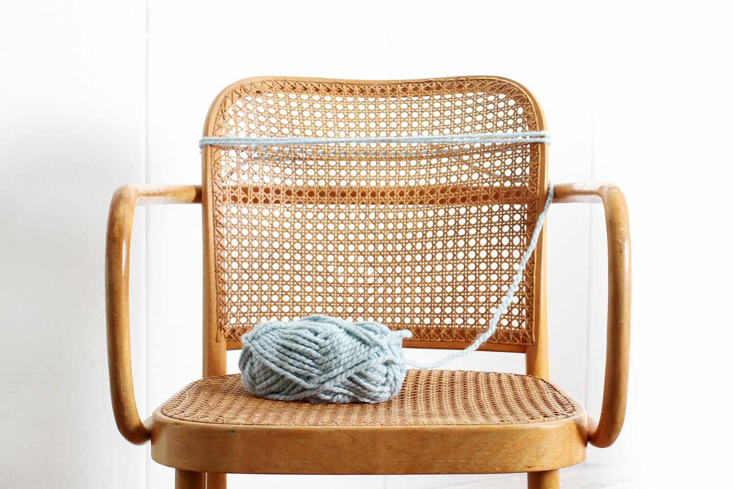 blue yarn starter wrap around back of wicker chair