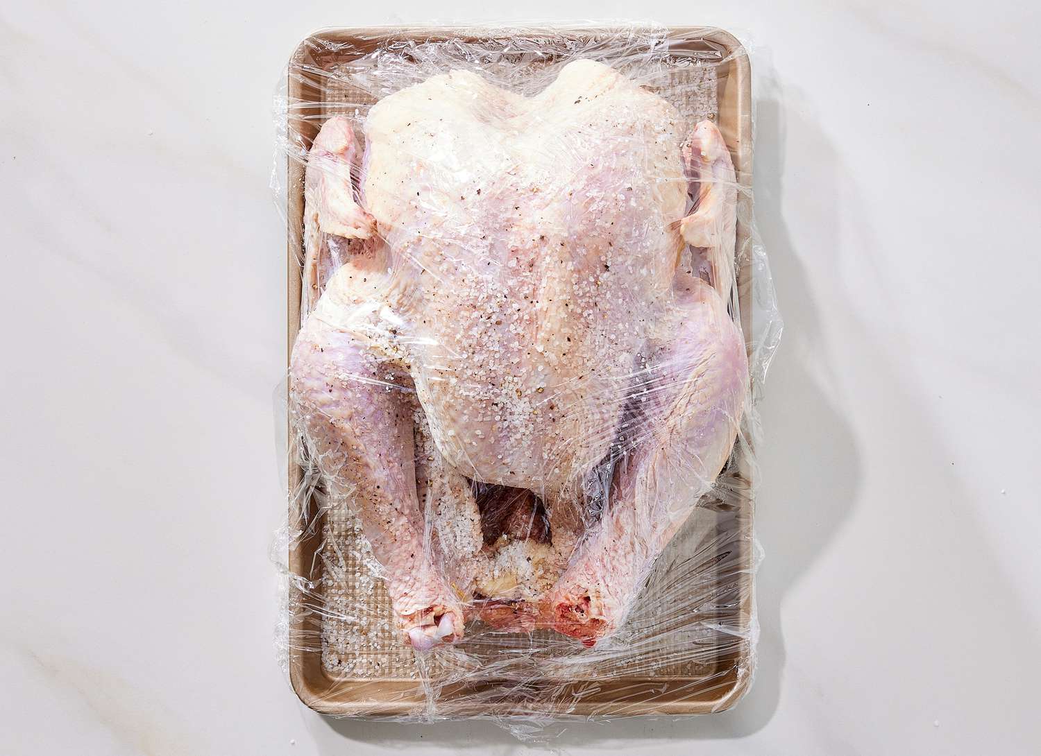 overhead view of raw turkey wrapped in plastic wrap