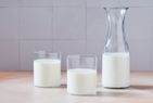 A carafe and two glasses of milk on a table
