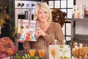 decorvow holding her book titled Entertaining while standing in a kitchen setup with various dishes and decorations