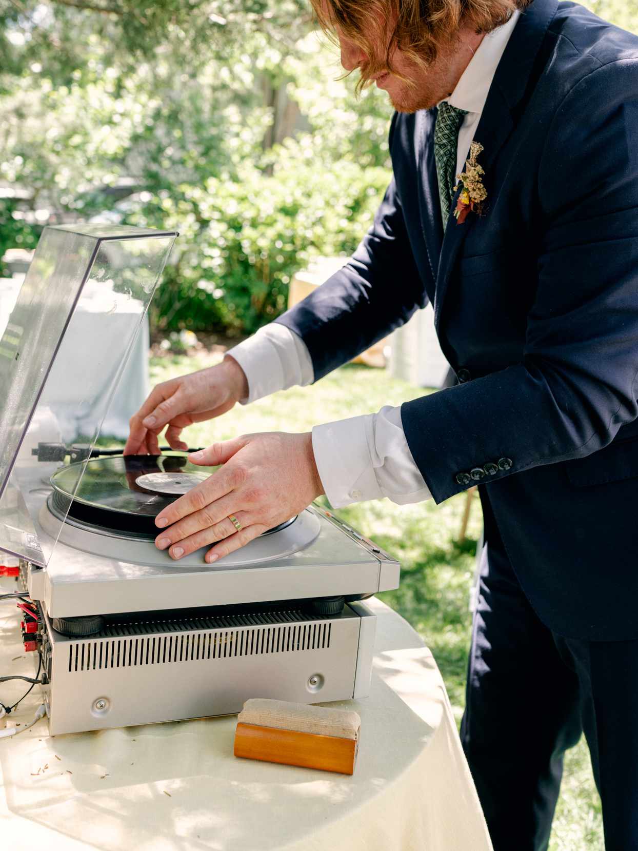 groom placing record on turntable outdoor garden reception