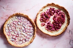 Two baked radish tarts with decorative sliced radishes on the surface, displayed on a marbled background