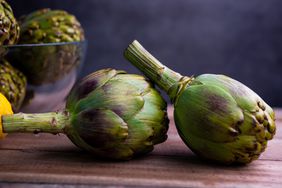 side view of two artichokes on wood surface