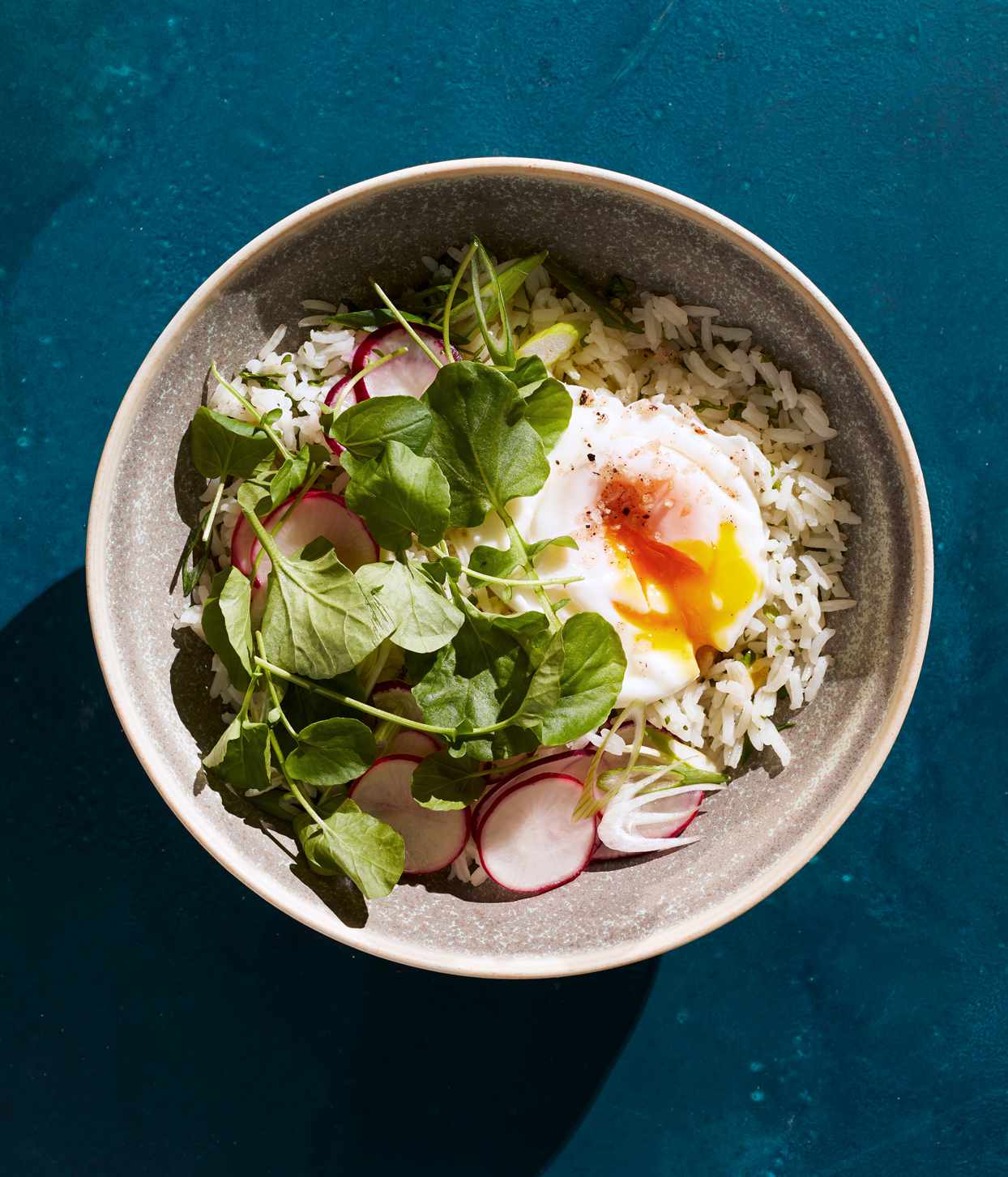 cilantro rice bowl with poached eggs and greens topped with radish slices