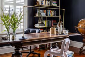 A study room featuring a wooden desk bookshelves stacked with books and a globe in the corner a chair positioned by the desk
