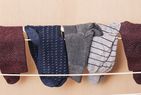 Several socks hanging on a drying rack indoors