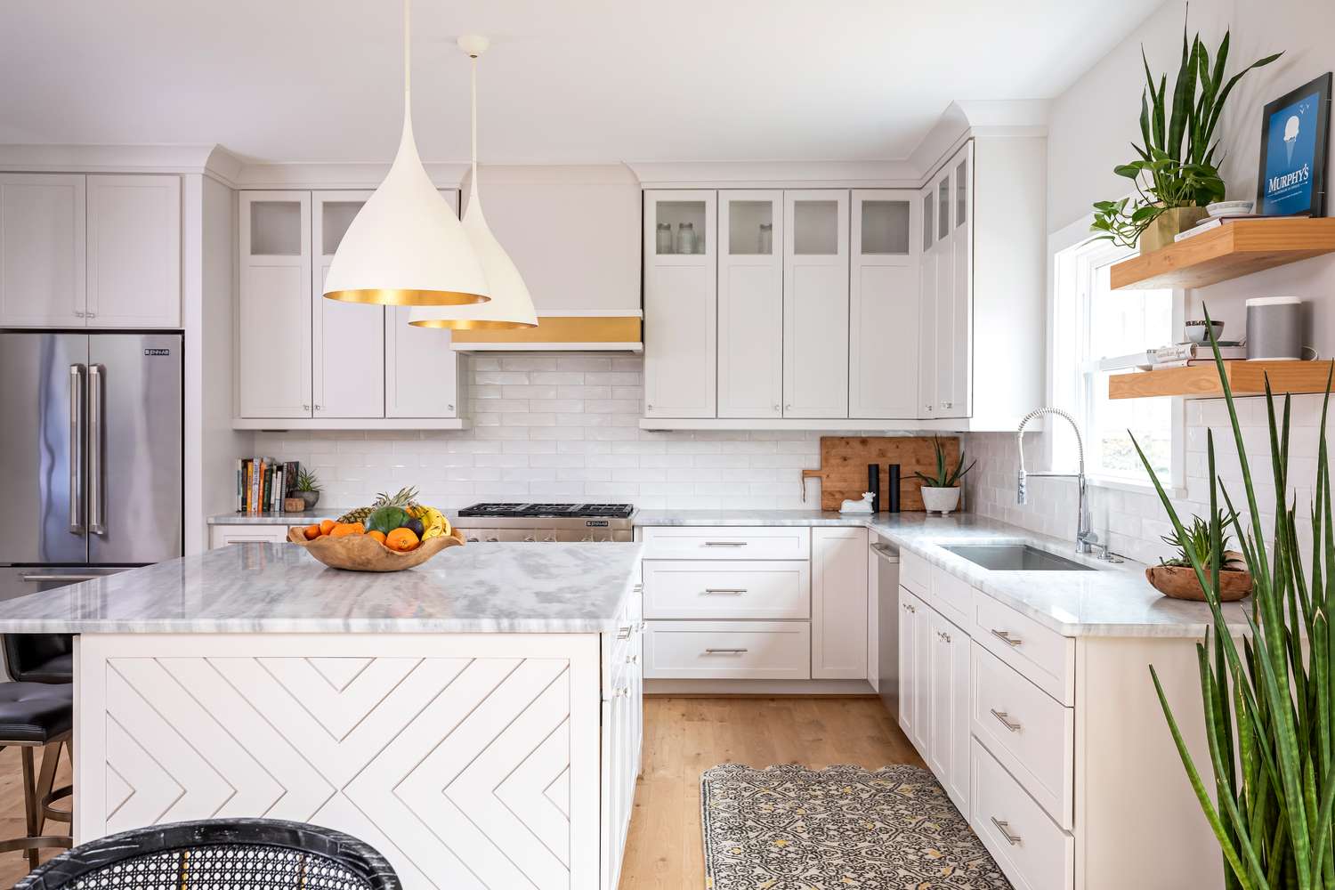 Modern kitchen with a marble countertop, an island, pendant lighting, and floating shelves with plants and decor