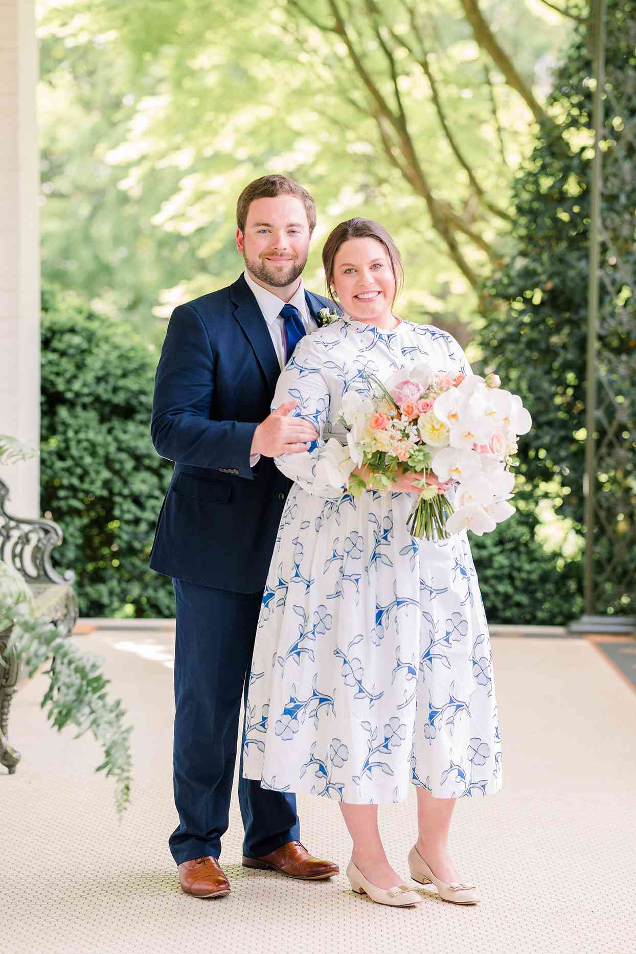groom stands behind bride holding her arm while they both smile