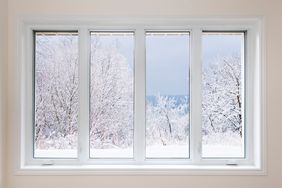 A view through a window showing a snowy landscape with trees