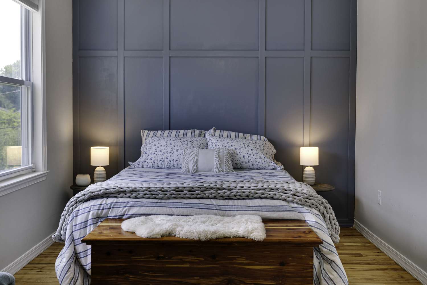A bedroom with a bed a wooden chest at the foot and two bedside lamps