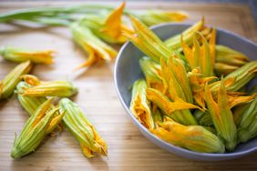 squash blossoms in a bowl and on bamboo surface
