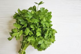 bunch of fresh parsley on white wooden surface