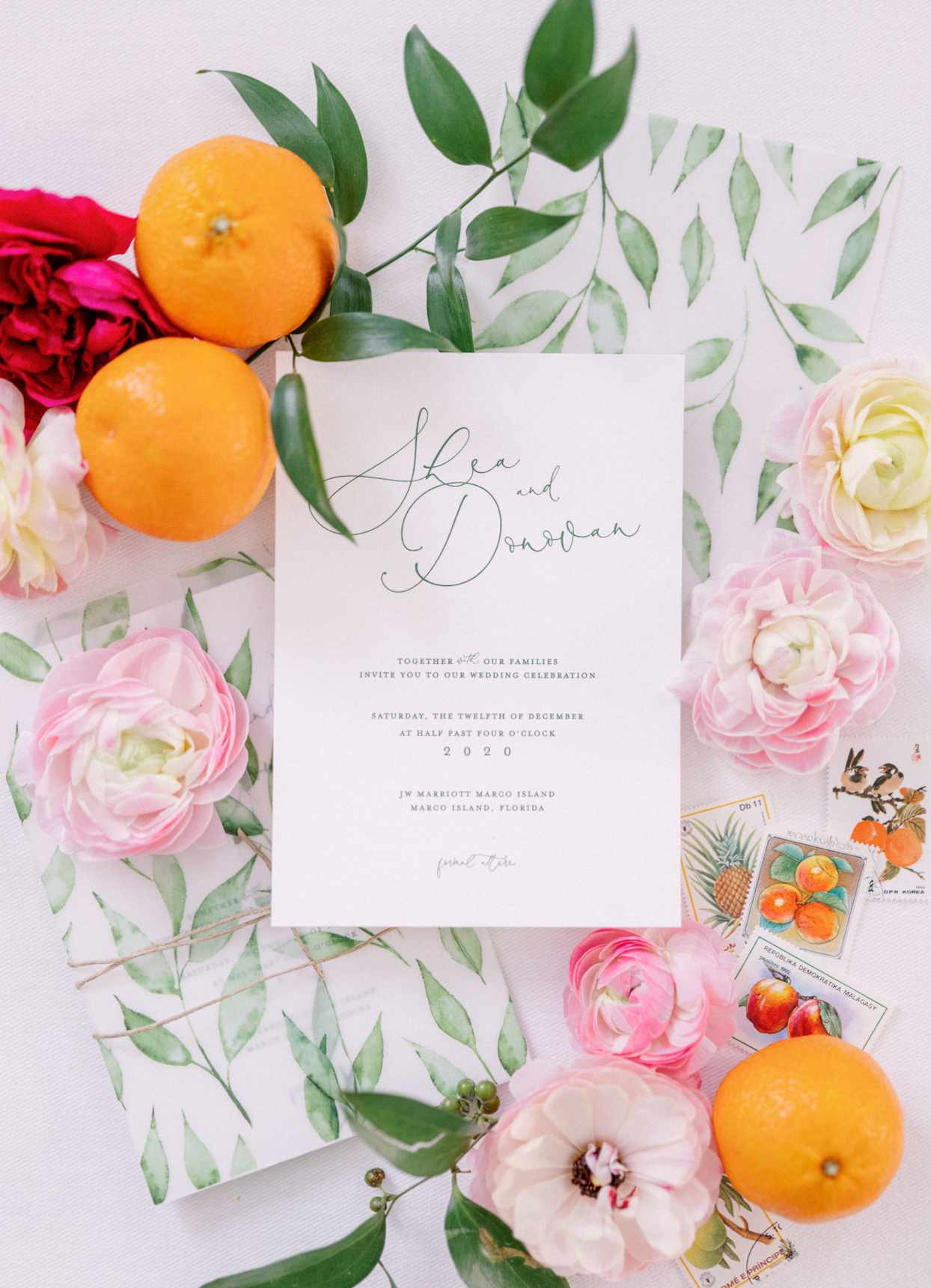 wedding invites with palm-frond green text, a jute tie, and a printed vellum wrap